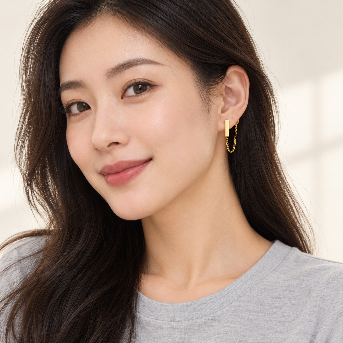 Gold-tone bar and chain-loop stud earrings, worn on an adult model